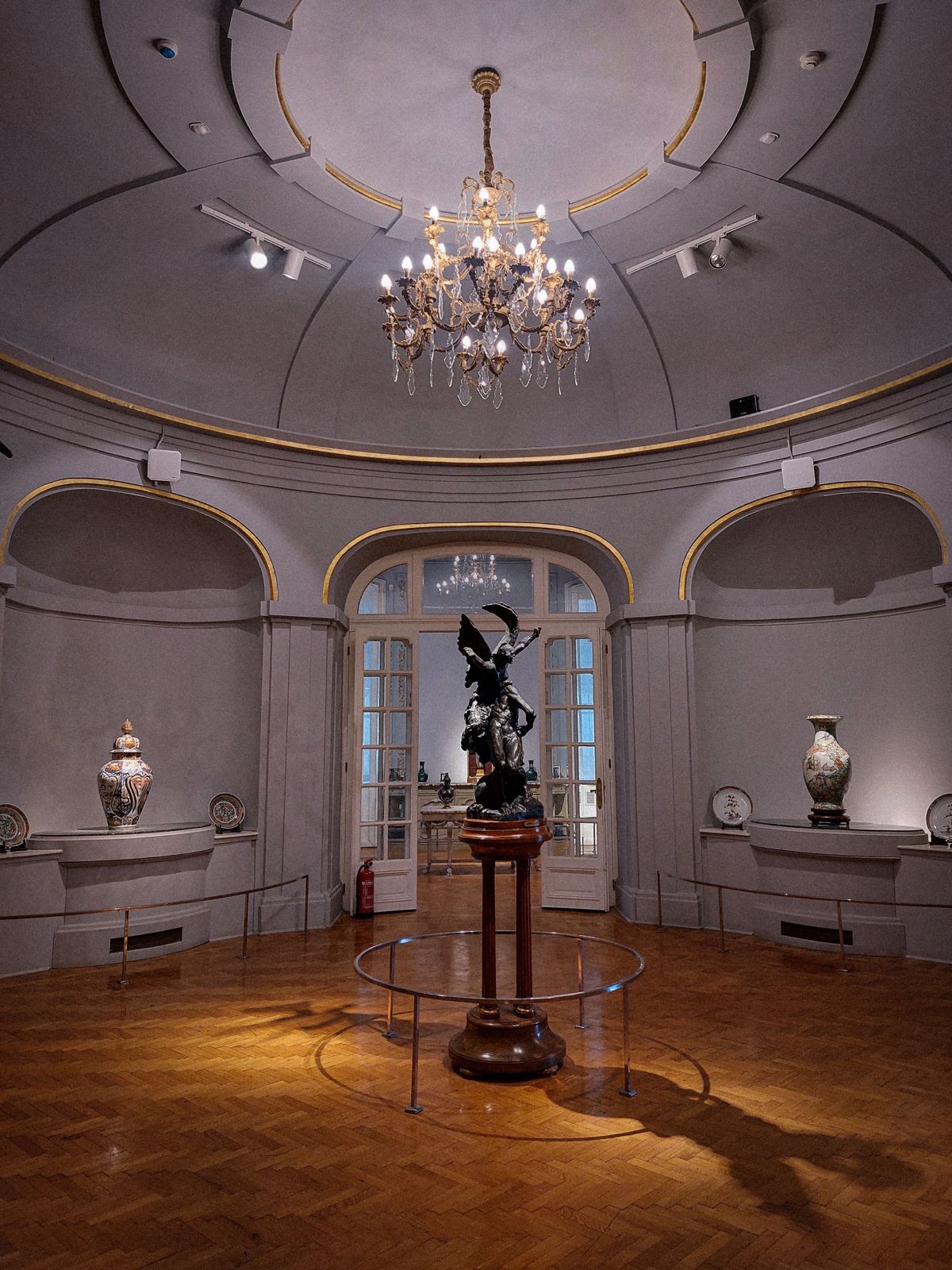 Round hall with a polished herringbone parquet floor under a chandelier