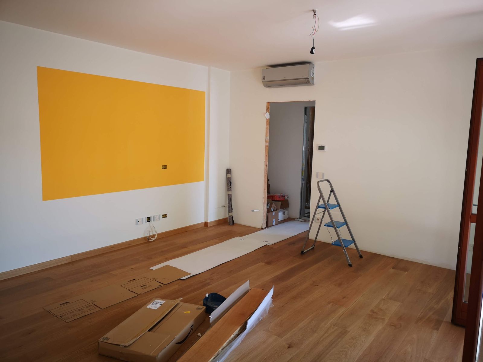 Room with a newly installed wood floor, protective paper runners and a step ladder